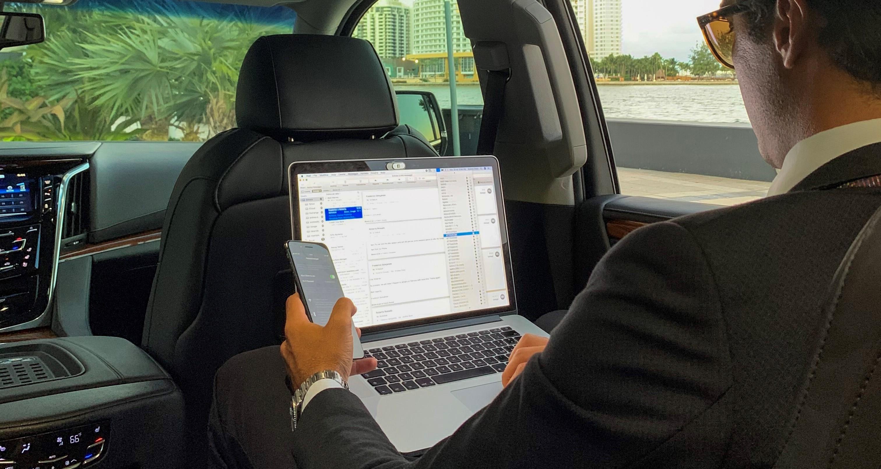 Businessman holding a mobile phone and a laptop in a limo